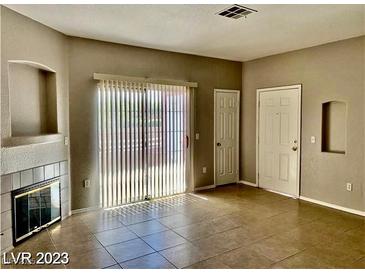 Open living room with sliding glass doors, tile floors, and a cozy fireplace at 4730 E Craig Rd # 1138, Las Vegas, NV 89115