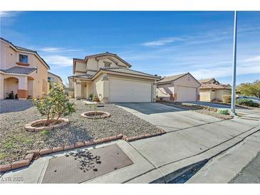 Tan two-story home featuring attached garage, landscaped yard and desert landscaping under bright blue skies at 9563 Grapeland Ave, Las Vegas, NV 89148