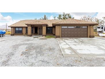 Charming single-story home with a well-maintained desert landscape and tile roof at 3051 S Rainbow Ave, Pahrump, NV 89048