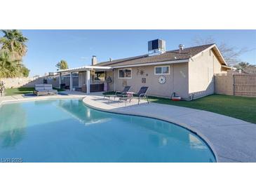 Inviting backyard oasis with a refreshing pool, lounge chairs, and covered patio, perfect for relaxation and outdoor entertaining at 4050 Royalhill Ave, Las Vegas, NV 89121