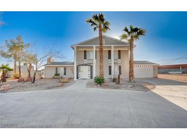 Two-story home featuring a grand entrance, palm trees, and a large, open driveway at 7477 Ullom Dr, Las Vegas, NV 89139