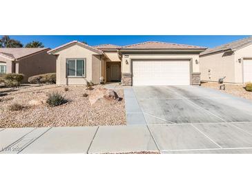 Tan single-story home with desert landscaping, a two-car garage, and a charming front entrance at 7649 Broadwing Dr, North Las Vegas, NV 89084