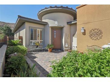 Charming front entrance with landscaped brick courtyard and inviting seating area with desert landscaping at 10057 Regency Canyon Way, Las Vegas, NV 89148
