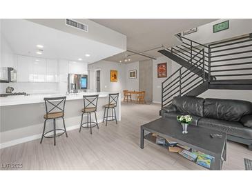 Bright, open-concept living space featuring modern kitchen, dining area, and staircase at 353 E Bonneville Ave # 752, Las Vegas, NV 89101