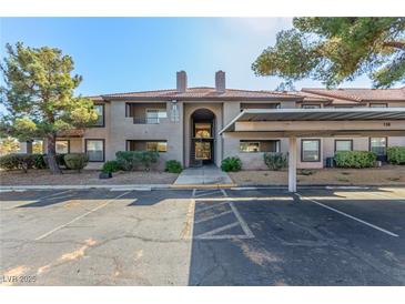 Exterior view of the condo featuring a terracotta tile roof, covered parking and desert landscaping at 2606 S Durango Dr # 232, Las Vegas, NV 89117