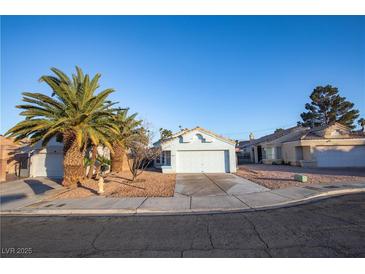 Single-story home featuring a two-car garage, xeriscape landscaping, and mature palm trees at 8072 Big Top Dr, Las Vegas, NV 89123