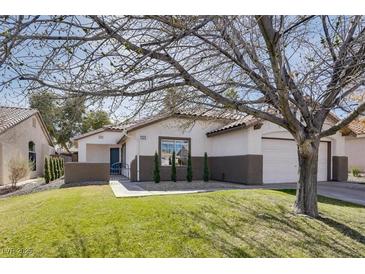 Charming single-story home featuring a well-manicured front yard with mature trees and an attached garage at 1323 Winter Solstice Ave, Henderson, NV 89014