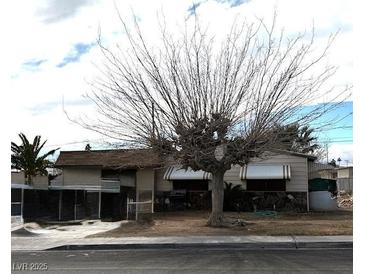 Modest single-story home featuring awnings and mature landscaping in a desert environment at 421 Miller Ave, North Las Vegas, NV 89030