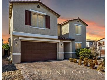 Two-story home featuring a brick driveway, stucco exterior, shutters, and a two-car garage at 10963 Mount Goyer St, Las Vegas, NV 89141