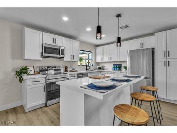 Modern kitchen featuring white cabinets, stainless steel appliances, and a stylish island with barstool seating at 2211 Frontier Ave, Las Vegas, NV 89106