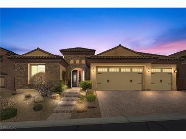 Charming single-story home with stone accents, three-car garage, and manicured landscaping at dusk at 2436 Chateau Napoleon Dr, Henderson, NV 89044