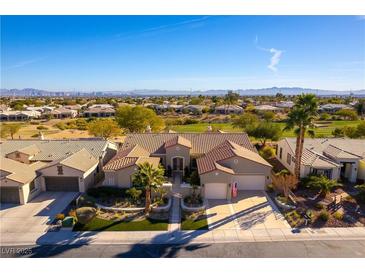 Expansive aerial view of a single story home with a tile roof situated on a golf course with mountain views at 4796 Riva De Romanza St, Las Vegas, NV 89135
