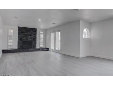 Spacious living room features a striking stone fireplace and ample natural light from large windows and french doors at 501 National St, Henderson, NV 89015