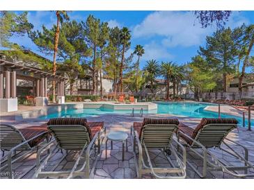 Community pool with lounge chairs surrounded by lush landscaping and palm trees on a sunny day at 108 Lemon Glaze St # 202, Las Vegas, NV 89145