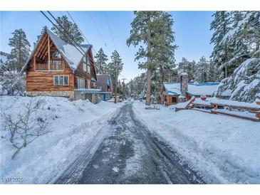 Charming street view of cabins blanketed with fresh snow and tall pine trees against a blue sky at 4587 Yellow Pine Ave, Mount Charleston, NV 89124