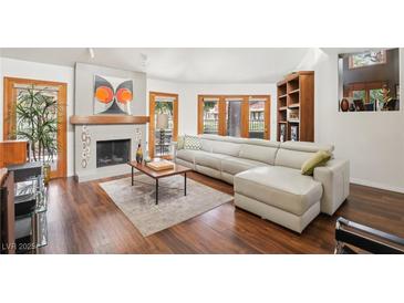 Bright living room with a sleek fireplace, hardwood floors, and a large sectional sofa at 7315 Mission Hills Dr, Las Vegas, NV 89113