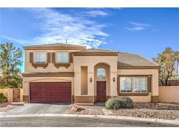 Two-story home featuring a red garage door, desert landscaping, and an arched entryway at 3401 Bedfordshire Pl, Las Vegas, NV 89129