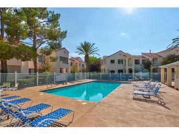 Community pool with lounge chairs surrounded by lush landscaping and lovely villa-style buildings on a bright sunny day at 4861 S Torrey Pines Dr # 201, Las Vegas, NV 89103