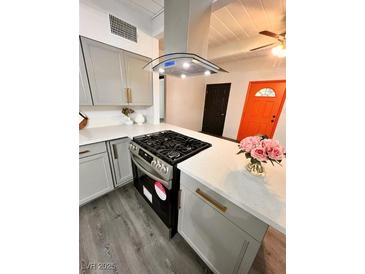 Modern kitchen featuring stainless steel appliances, quartz counters, gray cabinetry, and wood-look floors at 5013 Vermont Ave, Las Vegas, NV 89107