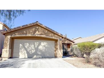 Tan single story home featuring a two car garage and desert landscaping at 6533 Adonis Heights Ave, North Las Vegas, NV 89086