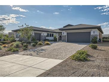 Beautiful single-story home featuring a three-car garage, desert landscaping, and a charming stone facade at 9475 W Rosada Way, Las Vegas, NV 89149