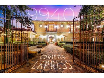 Elegant estate home with a gated entrance, lush landscaping, and stone pathway at 9940 Orient Express Ct, Las Vegas, NV 89145
