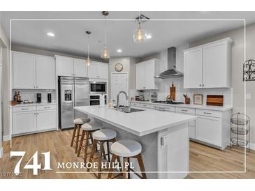 Bright open kitchen with a large island, stainless steel appliances, and modern pendant lighting at 741 Monroe Hill Pl, Henderson, NV 89011