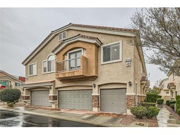 Charming townhome featuring three garage doors, a small balcony, and desert landscaping at 10147 Aspen Rose St # 101, Las Vegas, NV 89183