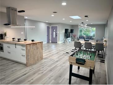 Spacious open-concept living area featuring a modern kitchen, dining space, and recreation area with a foosball table at 2250 Red Rock St, Las Vegas, NV 89146