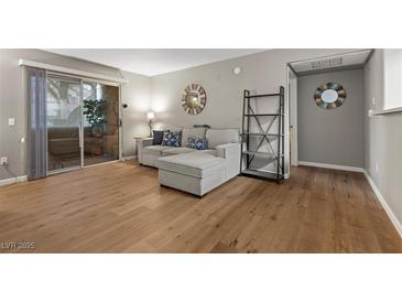 Bright living room features hardwood floors, neutral walls, sectional couch and slider to the outdoor patio at 2300 E Silverado Ranch Blvd # 1059, Las Vegas, NV 89183