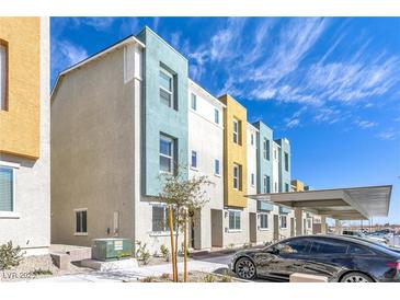 View of modern colorful townhomes with covered parking and well-maintained landscaping on a sunny day at 9160 Coral Cascade Ave, Las Vegas, NV 89141