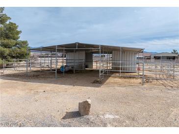 Outdoor barn structure with metal roof and horse fencing in a desert landscape, perfect for equestrian activities at 3581 Ranger Way, Pahrump, NV 89048