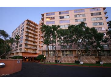 Multi-story building with balconies, mature landscaping, and covered entrance at 205 E Harmon Ave # 121, Las Vegas, NV 89169