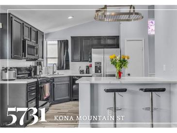 Modern kitchen features stainless steel appliances, a breakfast bar, and stylish dark cabinetry at 5731 Kona Mountain St, North Las Vegas, NV 89031