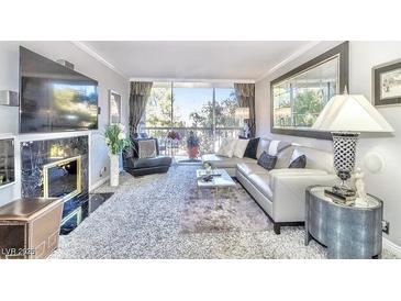 Bright living room with plush carpeting, large windows with view, and a decorative fireplace and entertainment center at 730 S Royal Crest Cir # 424, Las Vegas, NV 89169