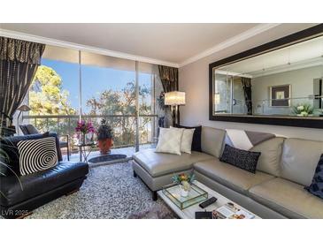 Inviting living room featuring a plush sectional sofa, balcony, and a serene outdoor view at 730 S Royal Crest Cir # 424, Las Vegas, NV 89169