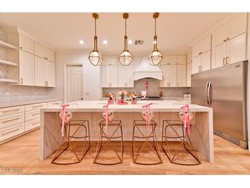 Modern kitchen features white cabinets, stainless steel appliances, marble backsplash, and a large kitchen island at 7565 N Torrey Pines Dr # A, Las Vegas, NV 89131