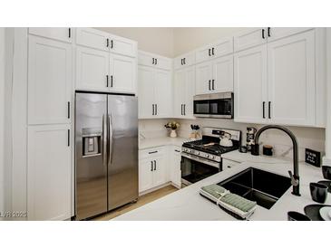 Modern kitchen with stainless steel refrigerator, gas range, and white cabinets and quartz countertops at 9741 Panorama Cliff Dr, Las Vegas, NV 89134