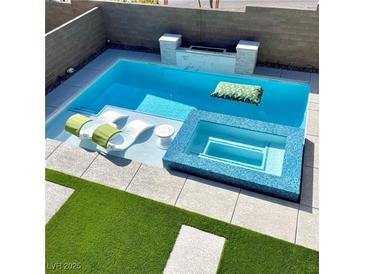 Inviting pool area features a spa, lounge chairs, and a built-in fire pit for relaxation and entertainment at 12451 Island Bells Ave, Las Vegas, NV 89138