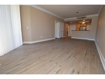 Bright living room boasts wood-look floors, neutral walls, and access to the kitchen at 220 E Flamingo Rd # 116, Las Vegas, NV 89169