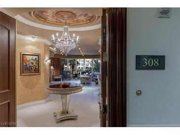 Elegant condo foyer features a crystal chandelier, round table, and an open view to the spacious living area at 1 Hughes Center Dr # 308, Las Vegas, NV 89169