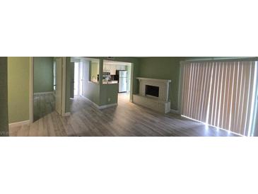 View of the living room with painted fireplace, wood-look floors, and sliding doors at 2981 Country Manor Ln # 2, Las Vegas, NV 89115