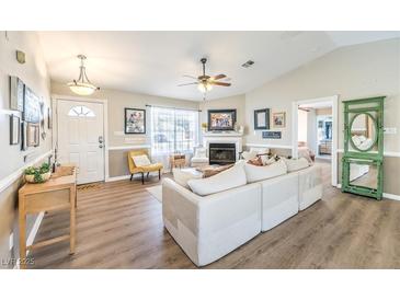 Open living room featuring a fireplace, ceiling fan, wood flooring, and neutral decor at 3192 Taylor St, Logandale, NV 89021