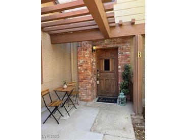 Charming brick-accented front entrance featuring a wooden pergola and outdoor seating area at 3449 Lorilou Ln # 2, Las Vegas, NV 89121