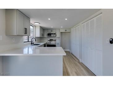 Bright kitchen featuring white cabinets, quartz countertops, stainless appliances, and wood-look tile flooring at 3484 Nightflower Ln # B, Las Vegas, NV 89121