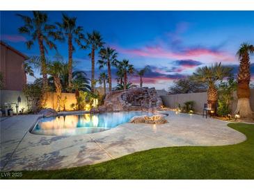 Beautiful pool with rock waterfall, ambient lighting, and lush landscaping at twilight at 3924 Diamond Ridge St, Las Vegas, NV 89129