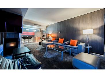 Contemporary living room with gray sofa, vibrant orange pillows, fireplace, and open kitchen concept at 4381 W Flamingo Rd # 2322/2320, Las Vegas, NV 89103