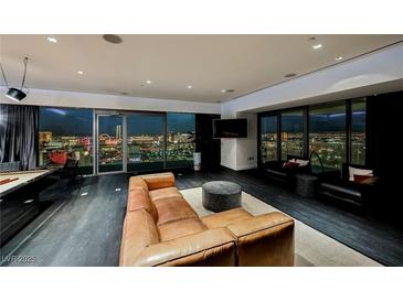 Modern living room features a leather sofa, sleek design, and panoramic city views through floor-to-ceiling windows at 4381 W Flamingo Rd # 5708, Las Vegas, NV 89103