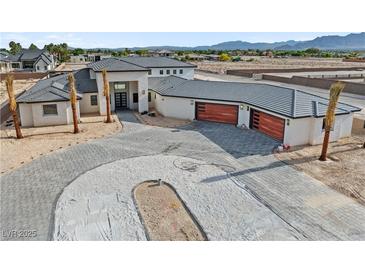 Modern home featuring white stucco, dark grey roof, spacious driveway, and wooden garage doors at 6383 Horse Dr, Las Vegas, NV 89131
