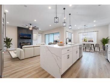 Open-concept living space with modern kitchen, dining area, fireplace, and large island at 350 Robledo St, Las Vegas, NV 89138